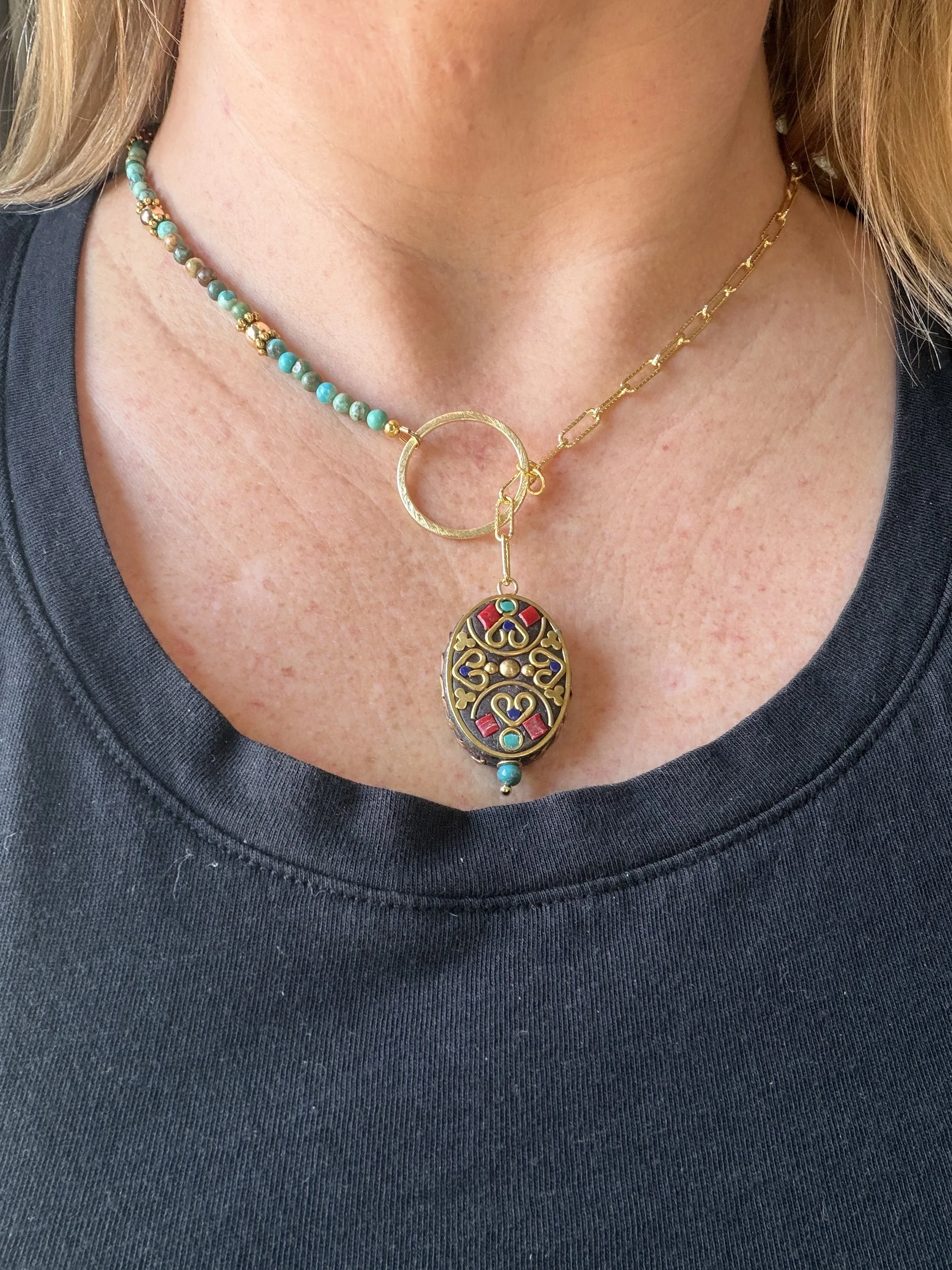 woman wearing handmade asymmetrical necklace with Tibetan brass turquoise coral lapis inlay pendant and genuine turquoise beading