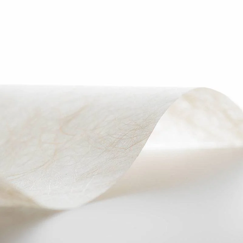 Close-up of a curled, translucent tissue paper with a textured surface against a white background.