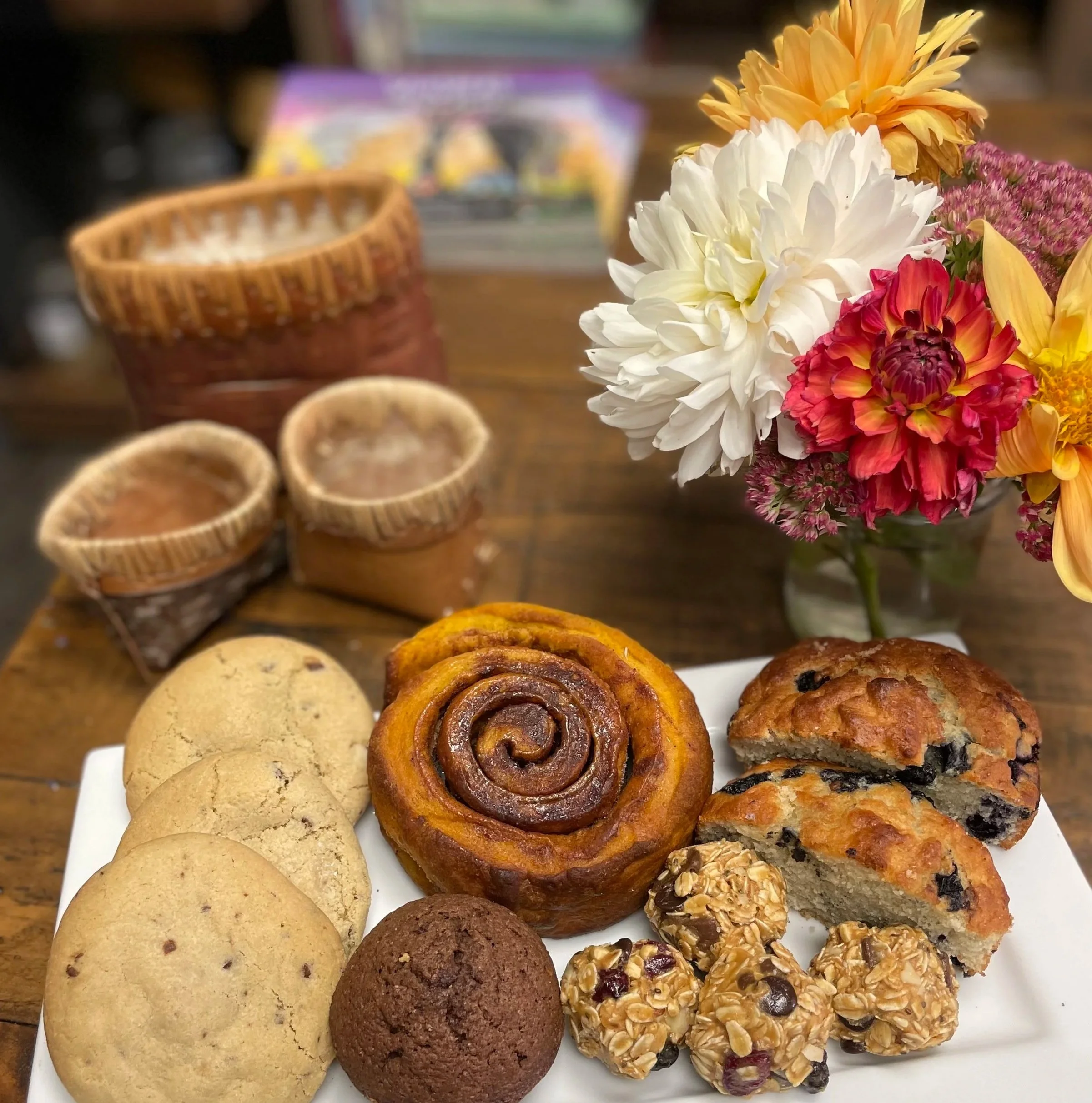 Assorted cookies and a bouquet of flowers on a white plate.