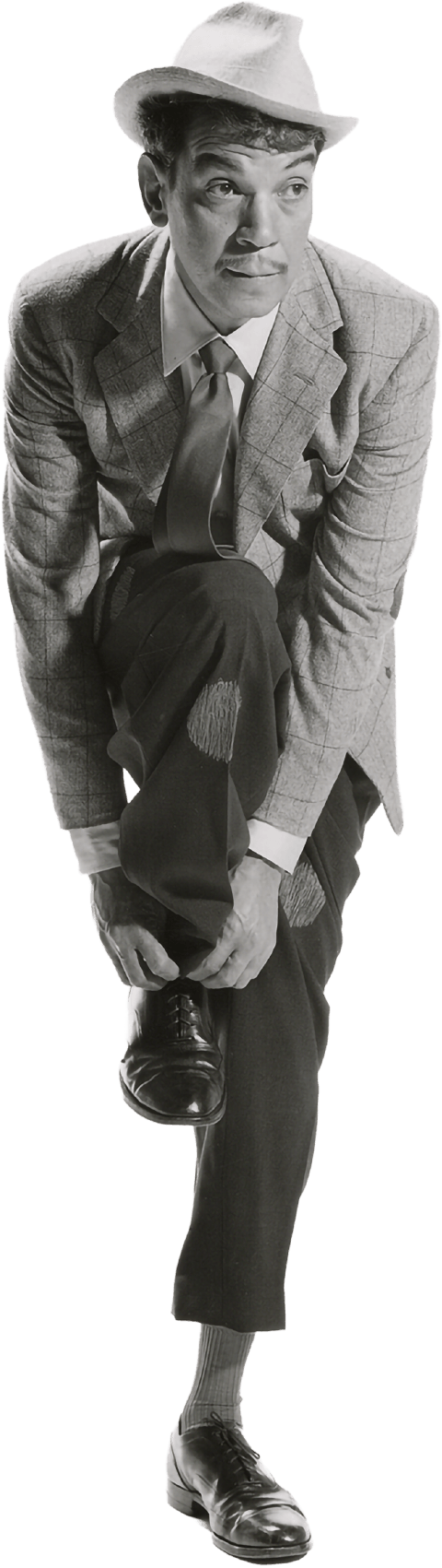 Cantinflas con sombrero, saco a cuadros, camisa blanca, corbata y pantalones anchos con parches, ajustados con zapatos formales. Su pierna derecha está levantada del piso mientras que él abrocha la agujeta de un zapato.