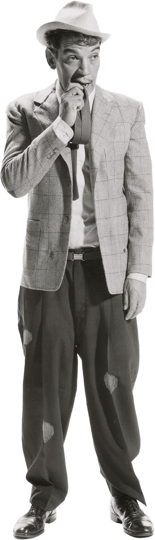 Cantinflas con sombrero, saco a cuadros, camisa blanca, corbata y pantalones anchos con parches, ajustados con zapatos formales. Mordiendo su misma corbata como un gesto de nerviosismo.