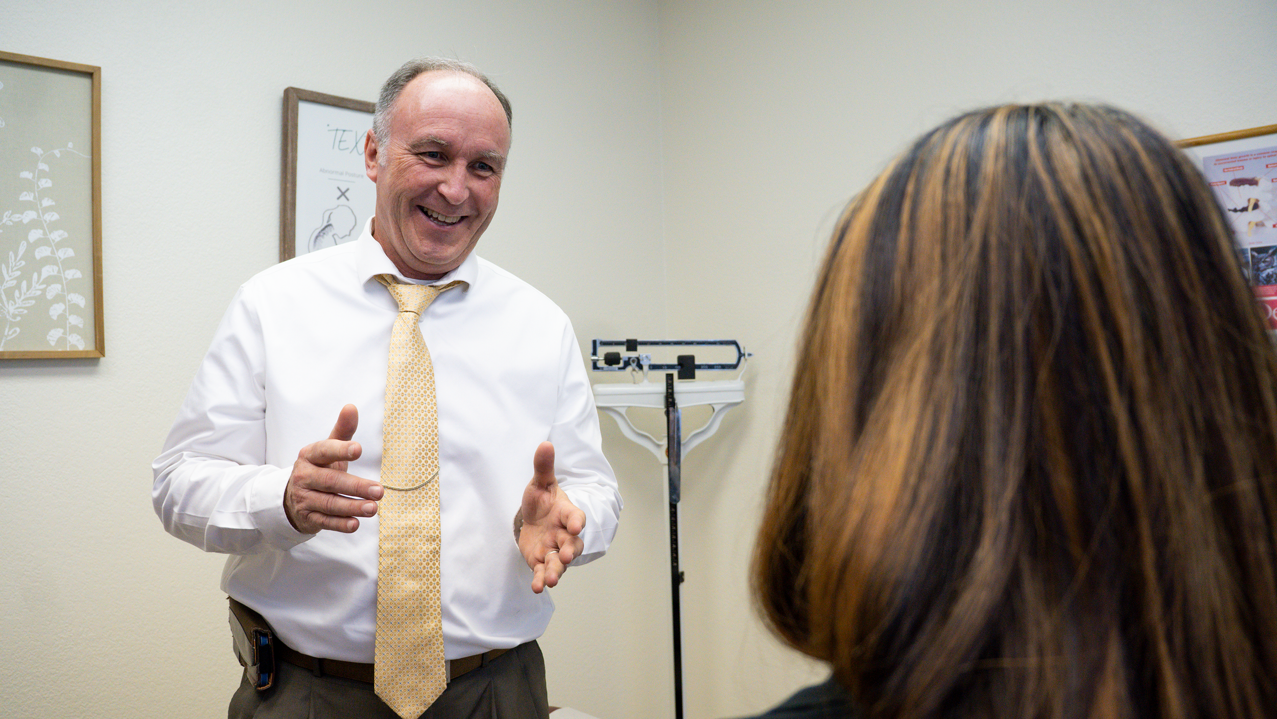 A male doctor smiling and talking to a woman in a medical examination room.