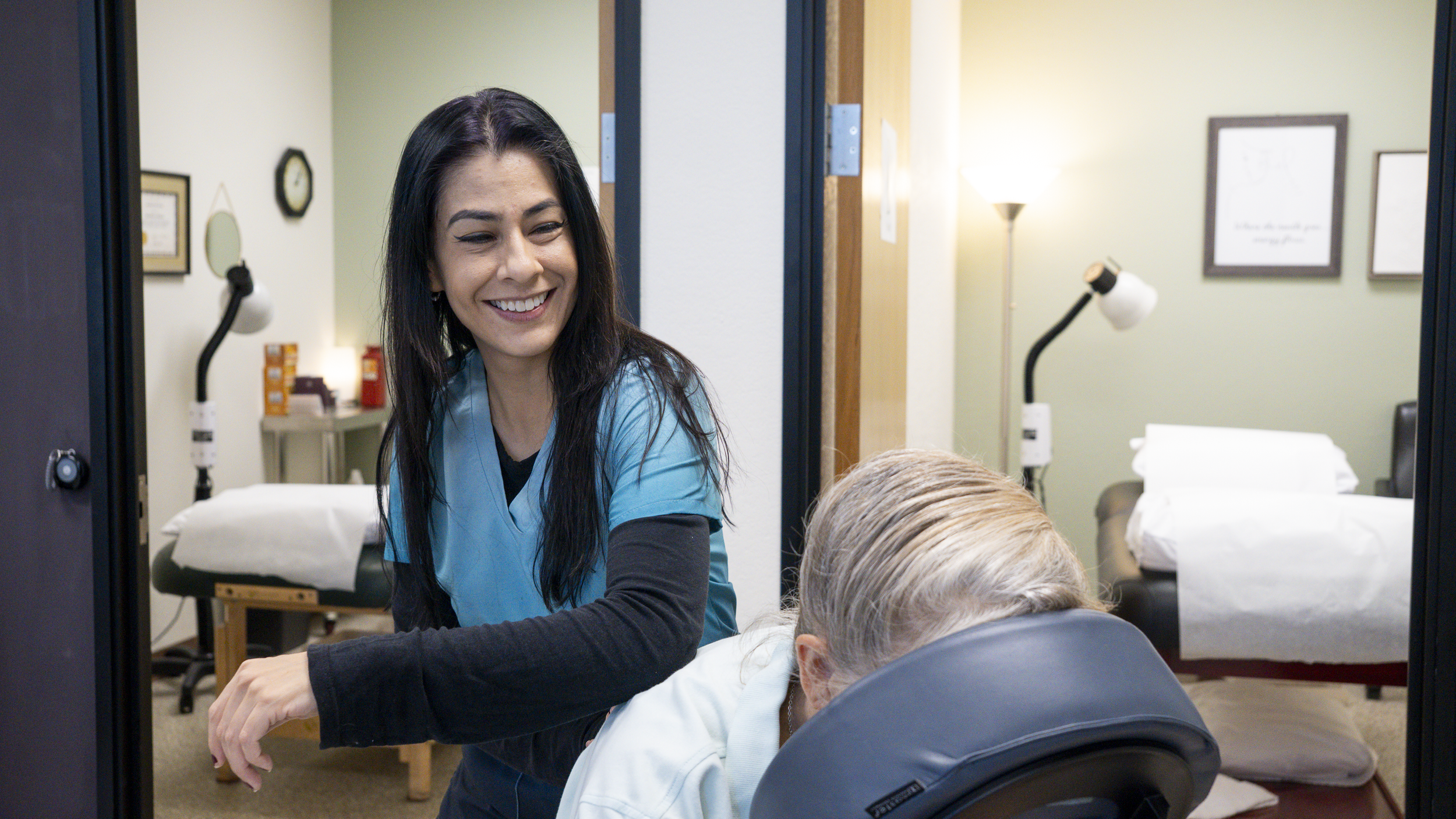 A nurse smiling at an elderly patient lying on a table in a clinic room.