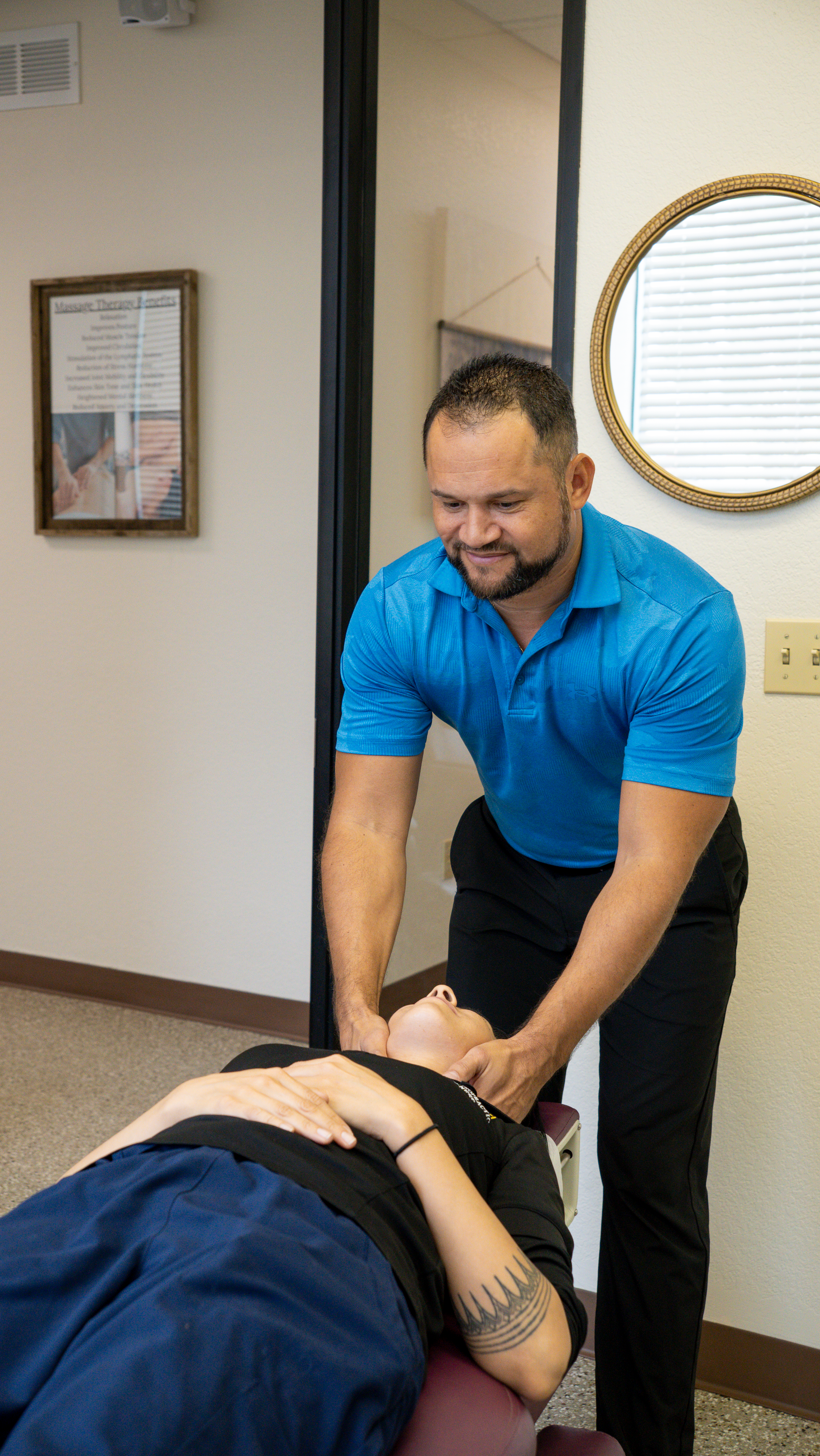 A man providing chiropractic adjustment to a woman lying on a chiropractic table in an office setting.