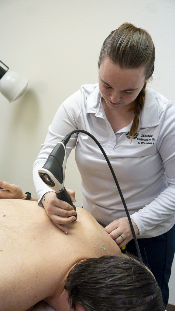 A chiropractor performing an ultrasound on a patient in a clinical setting.