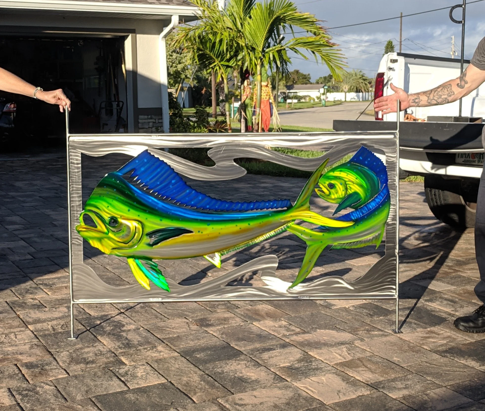 Colorful aluminum artwork of a fish mounted on a stainless frame for a railing