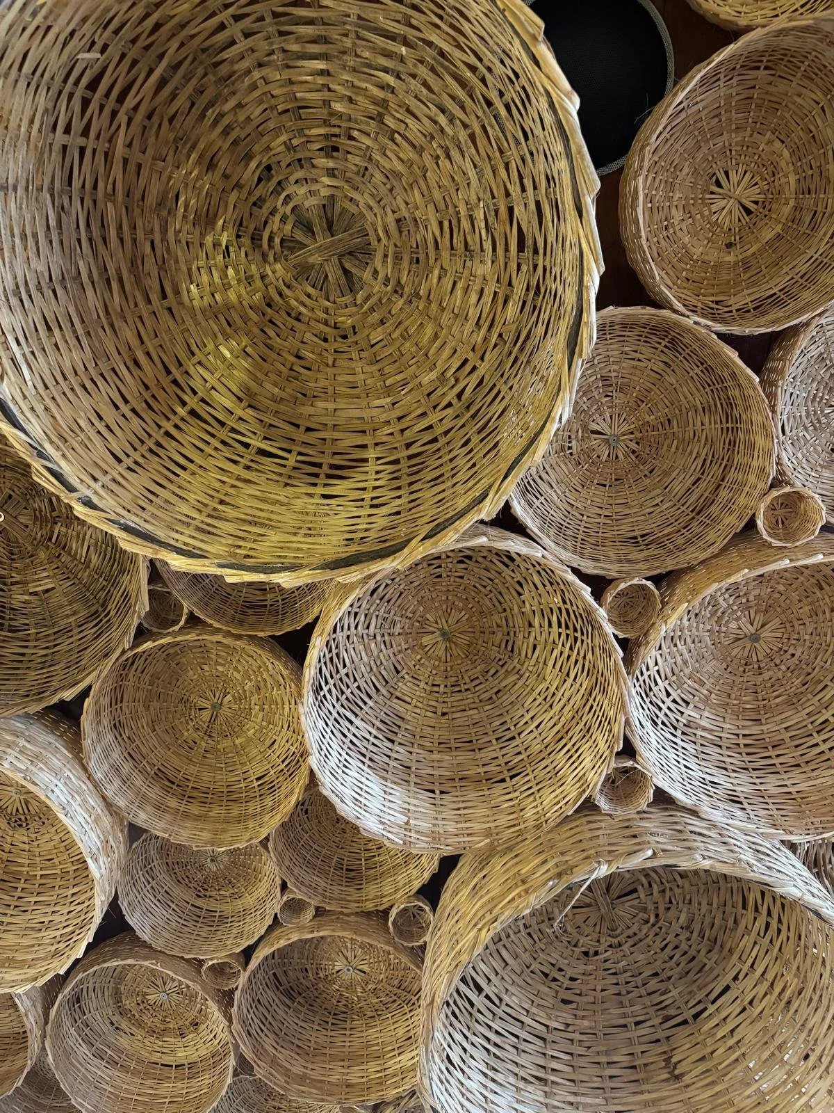 A collection of empty woven wicker baskets stacked together, viewed from the top.