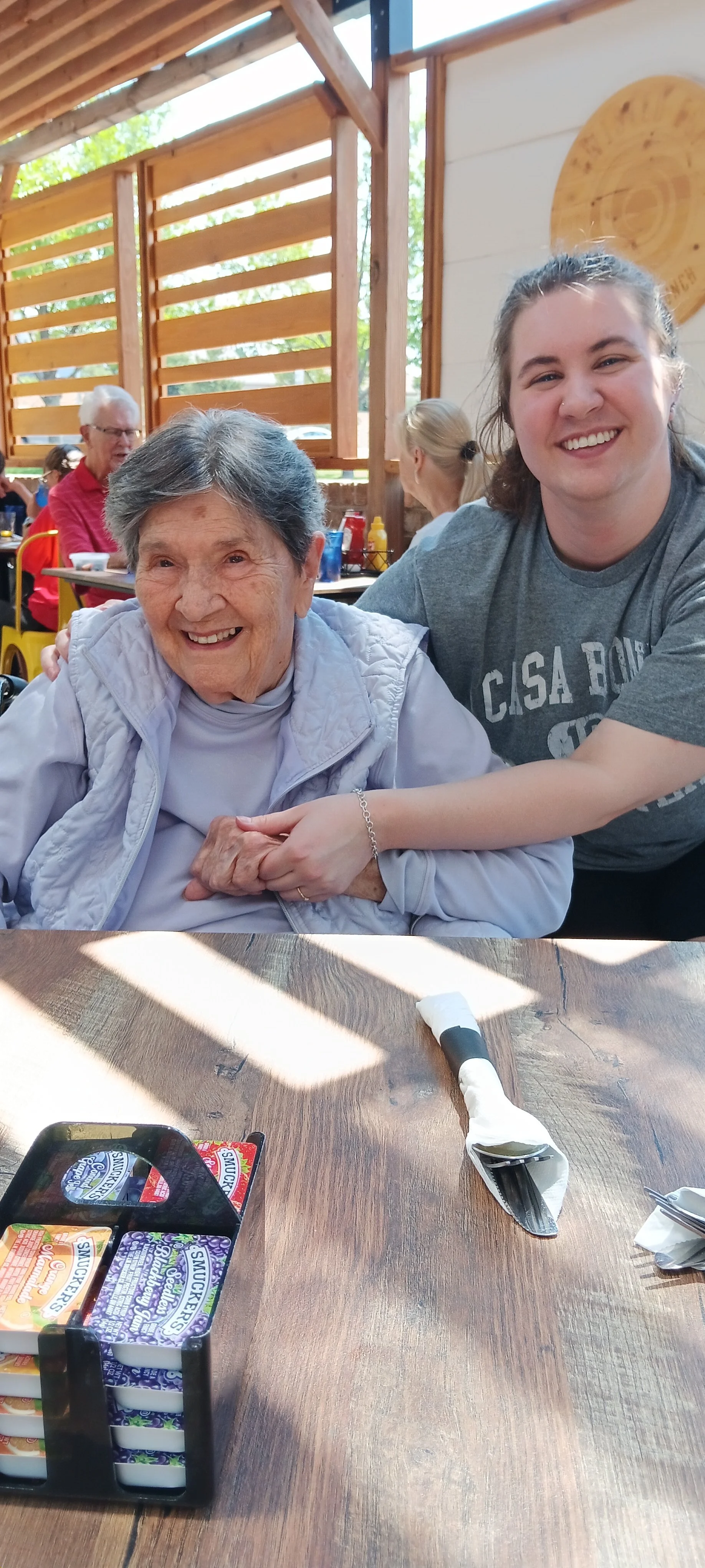 A young woman and an elderly woman smiling at a restaurant table.