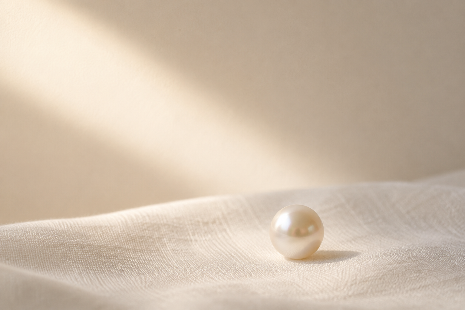 A single pearl resting on soft fabric, symbolizing Parelora’s philosophy of transformation through self-return.