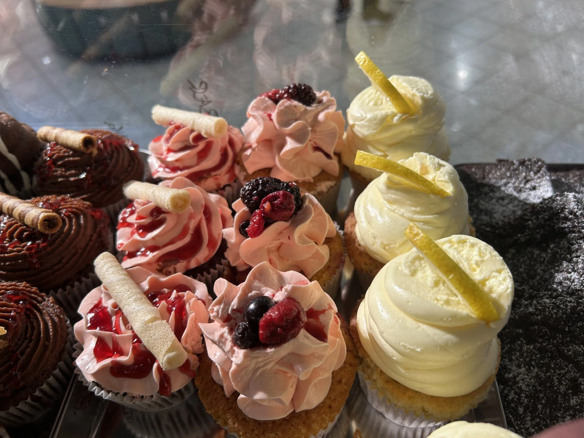 Diverse cupcakes med frosting, bær, sitronstaver og sjokolade.