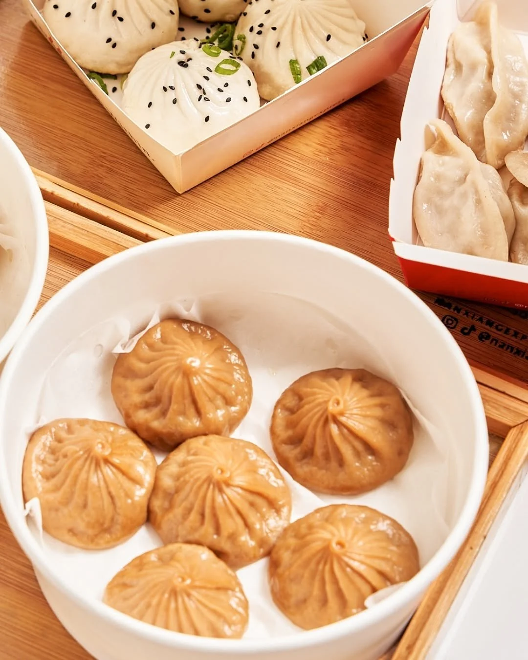 Assorted steamed dumplings and bao buns on a wooden tray