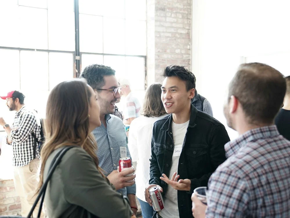 Group of four men and woman talking in a bright room networking.