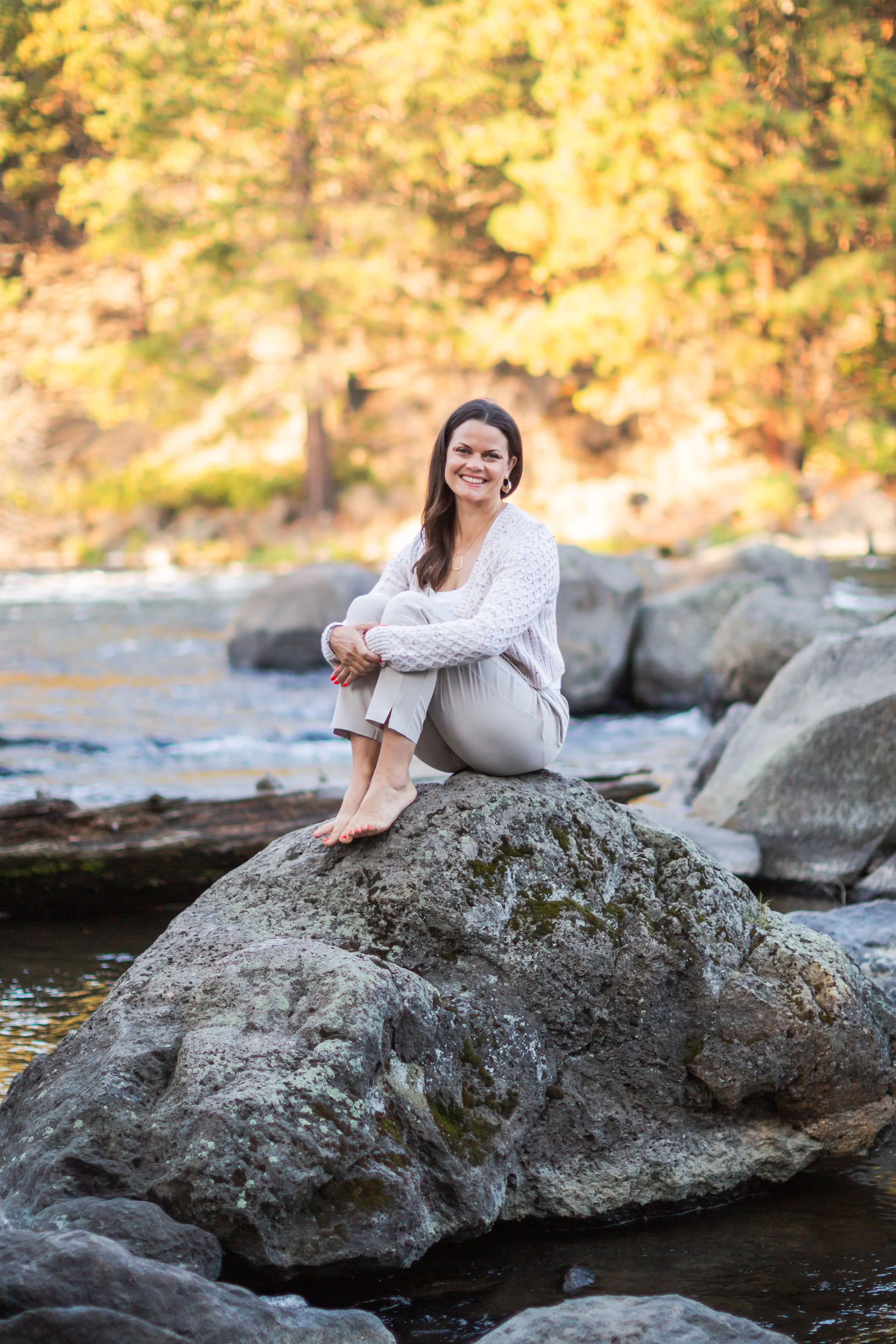 Angie Watson sitting beside a river in Bend, Oregon.