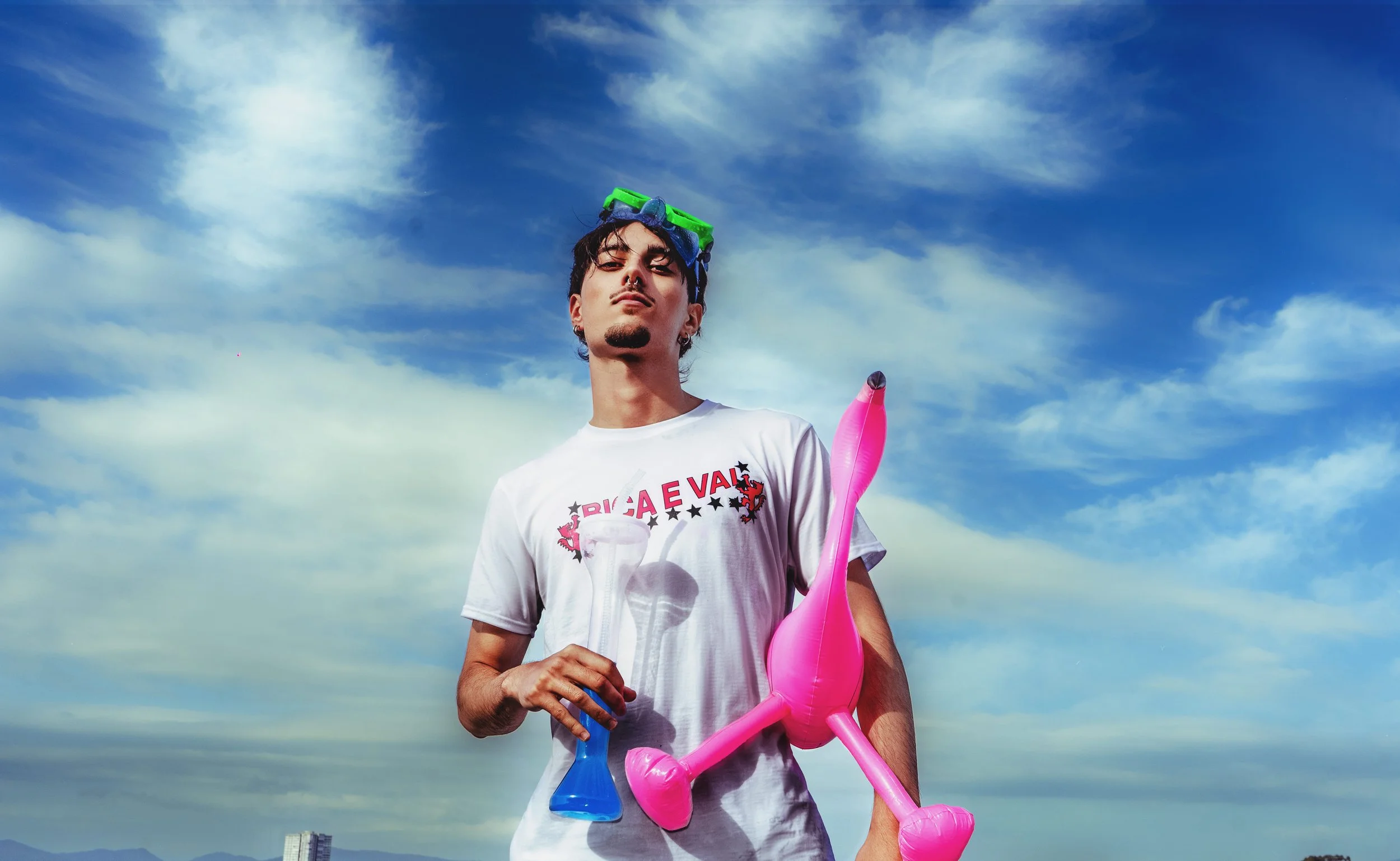 Joven sosteniendo globos de colores contra un cielo nublado.