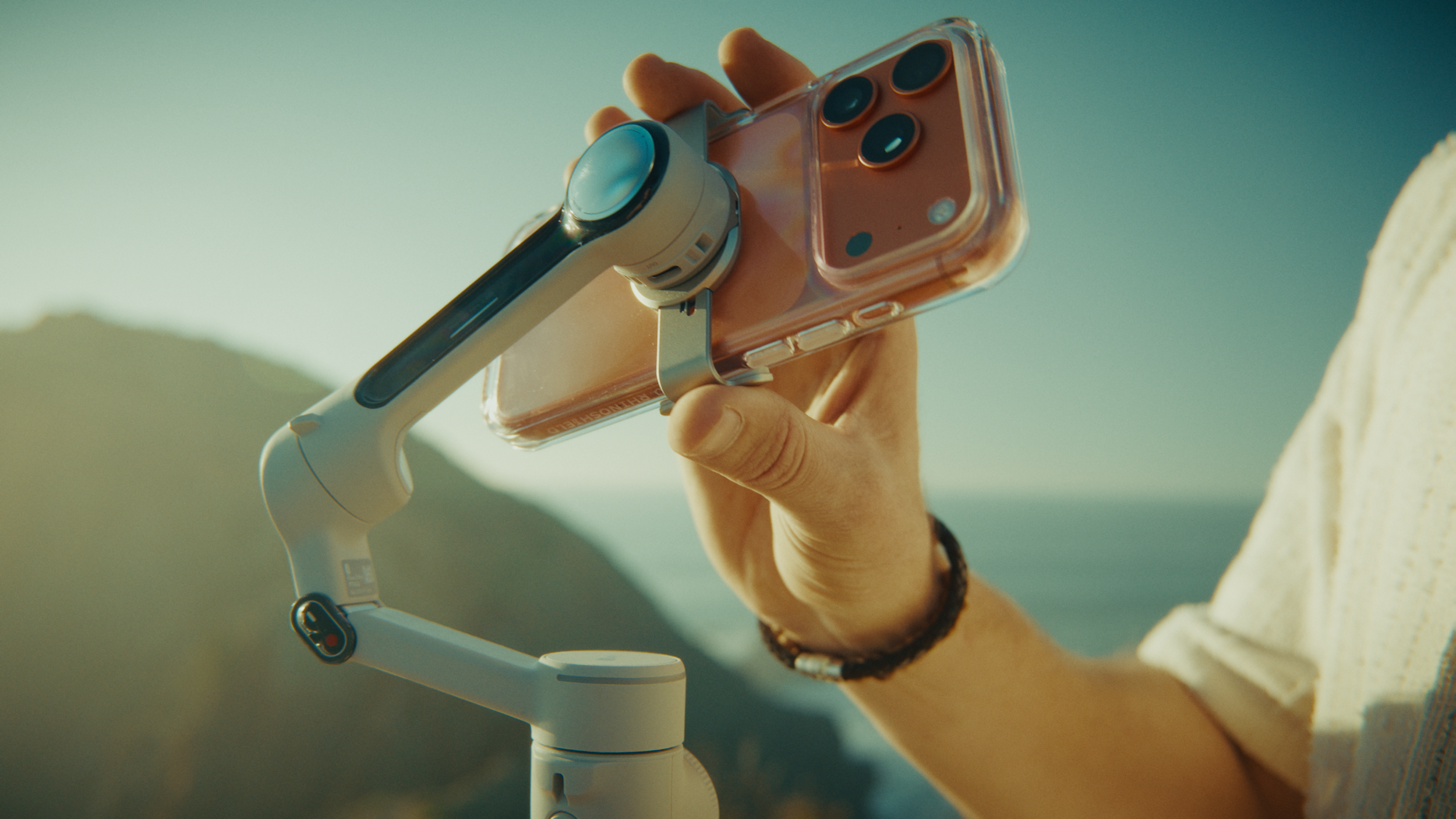 Close-up of a person's hand holding a smartphone mounted on a small drone.
