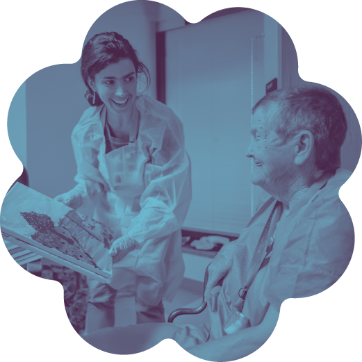A young female healthcare worker showing an X-ray to an elderly male patient in a hospital room.