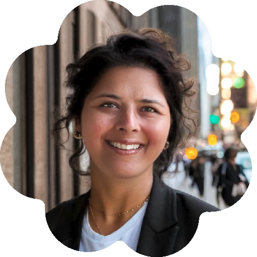 Nisha Sajnani, the Professor and Director of Drama Therapy at NYU Steinhardt and the Founding Co-Director at Jameel Arts & Health Lab, smiling outdoors on a city street, with blurred pedestrians and traffic in the background.
