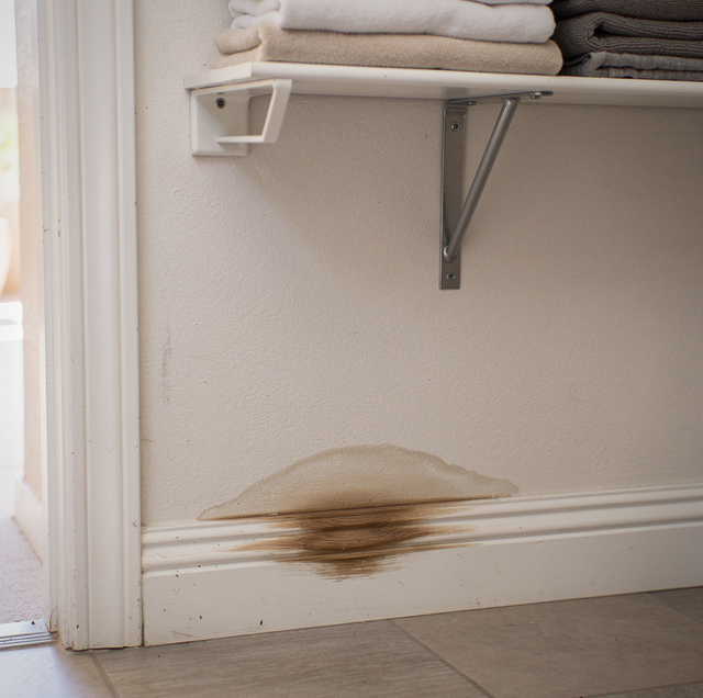 Folded towels on a wall shelf above a stained white baseboards.