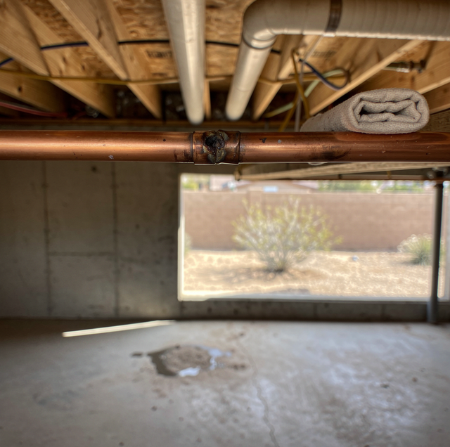 Weathered copper pipe with pinhole leak at joint