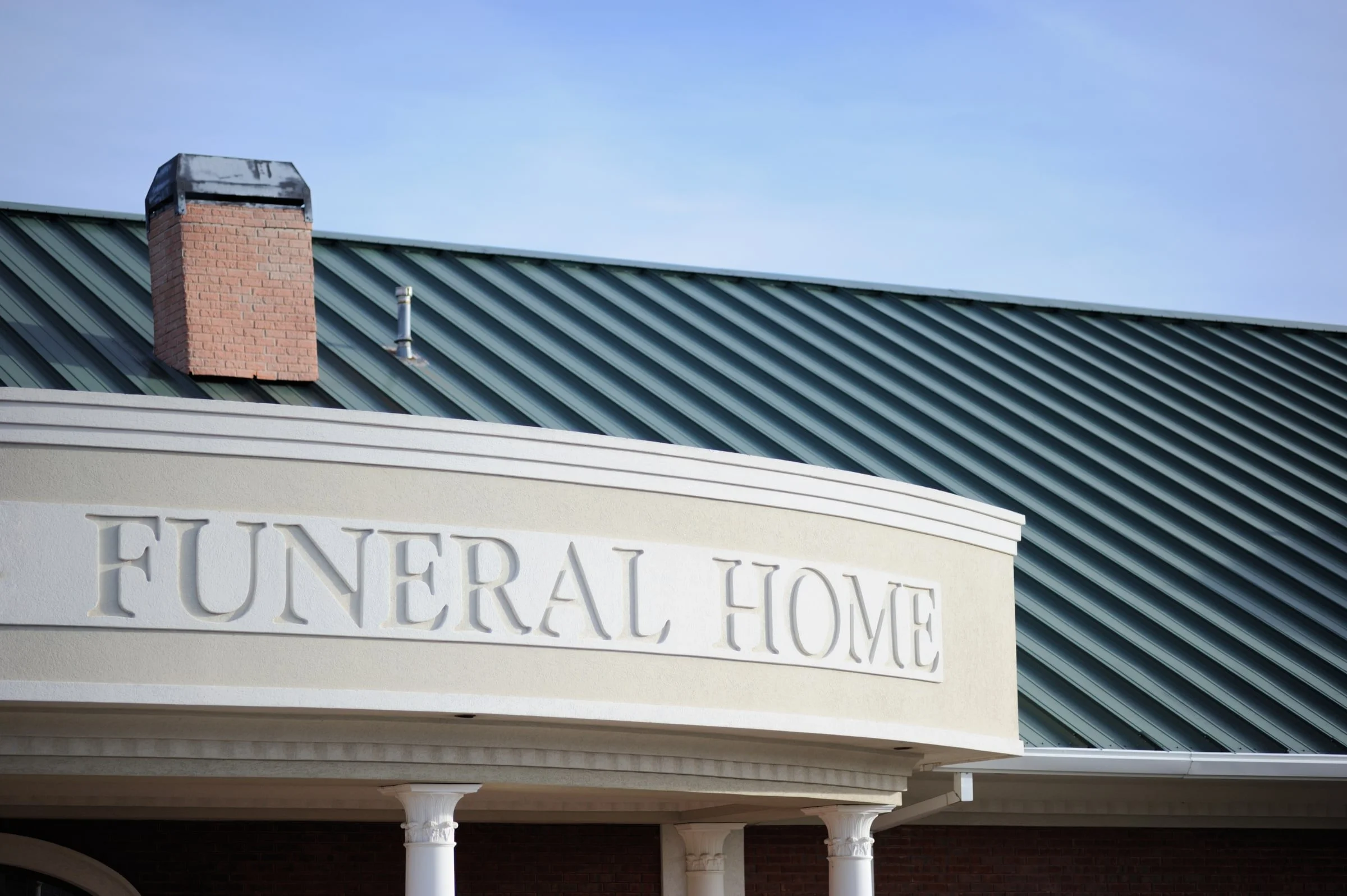 Funeral home exterior with a green metal roof