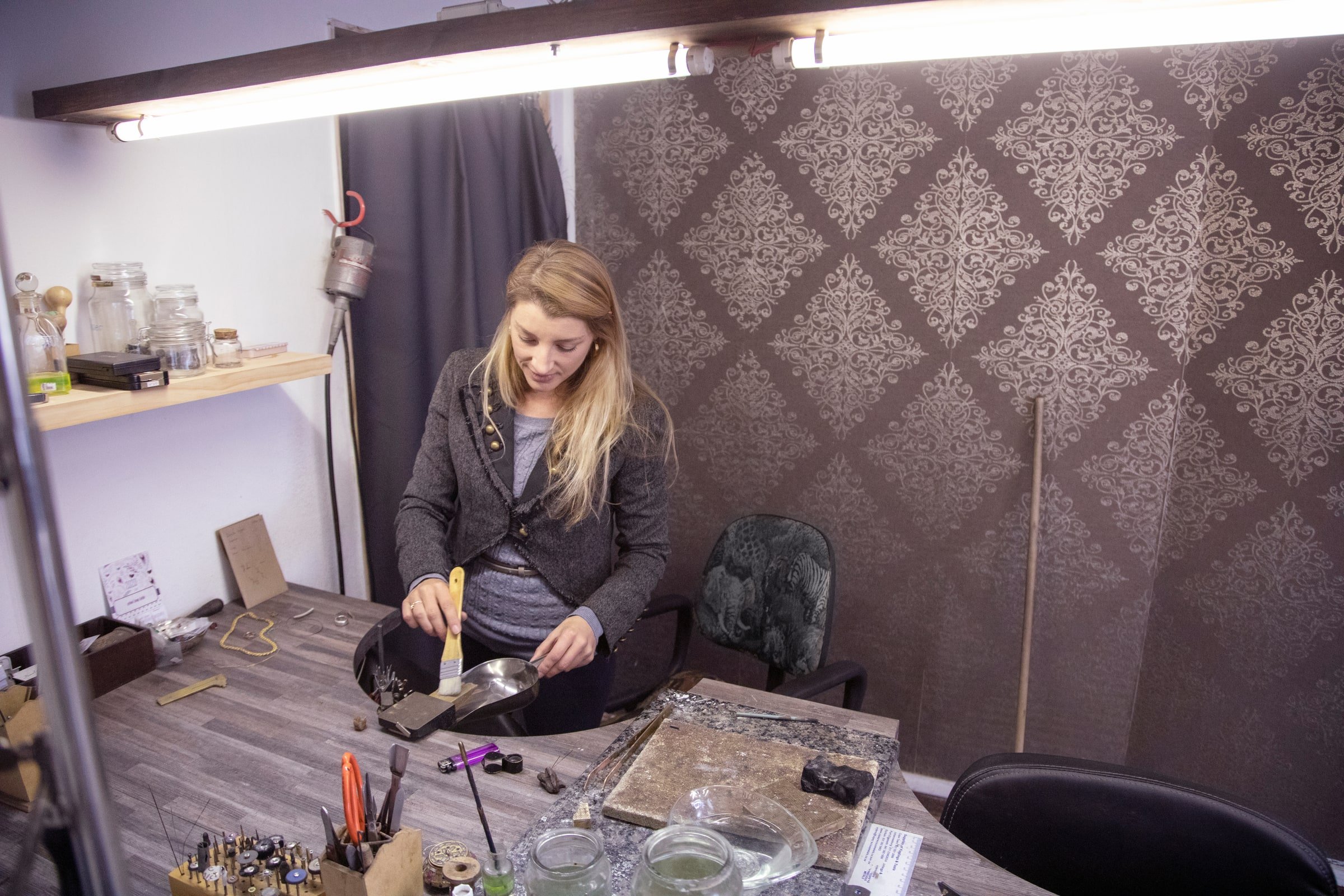 Jeweler collecting bench sweeps from a jewelry workbench
