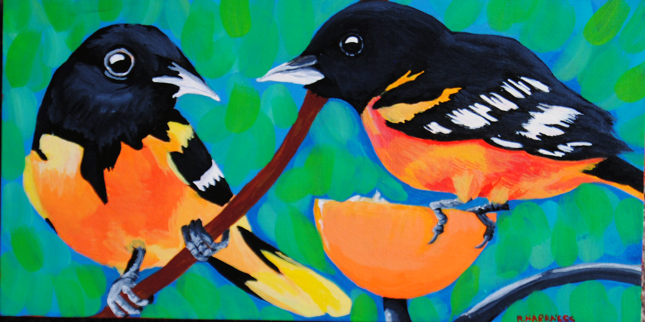 two oriels sitting on a branch with an orange