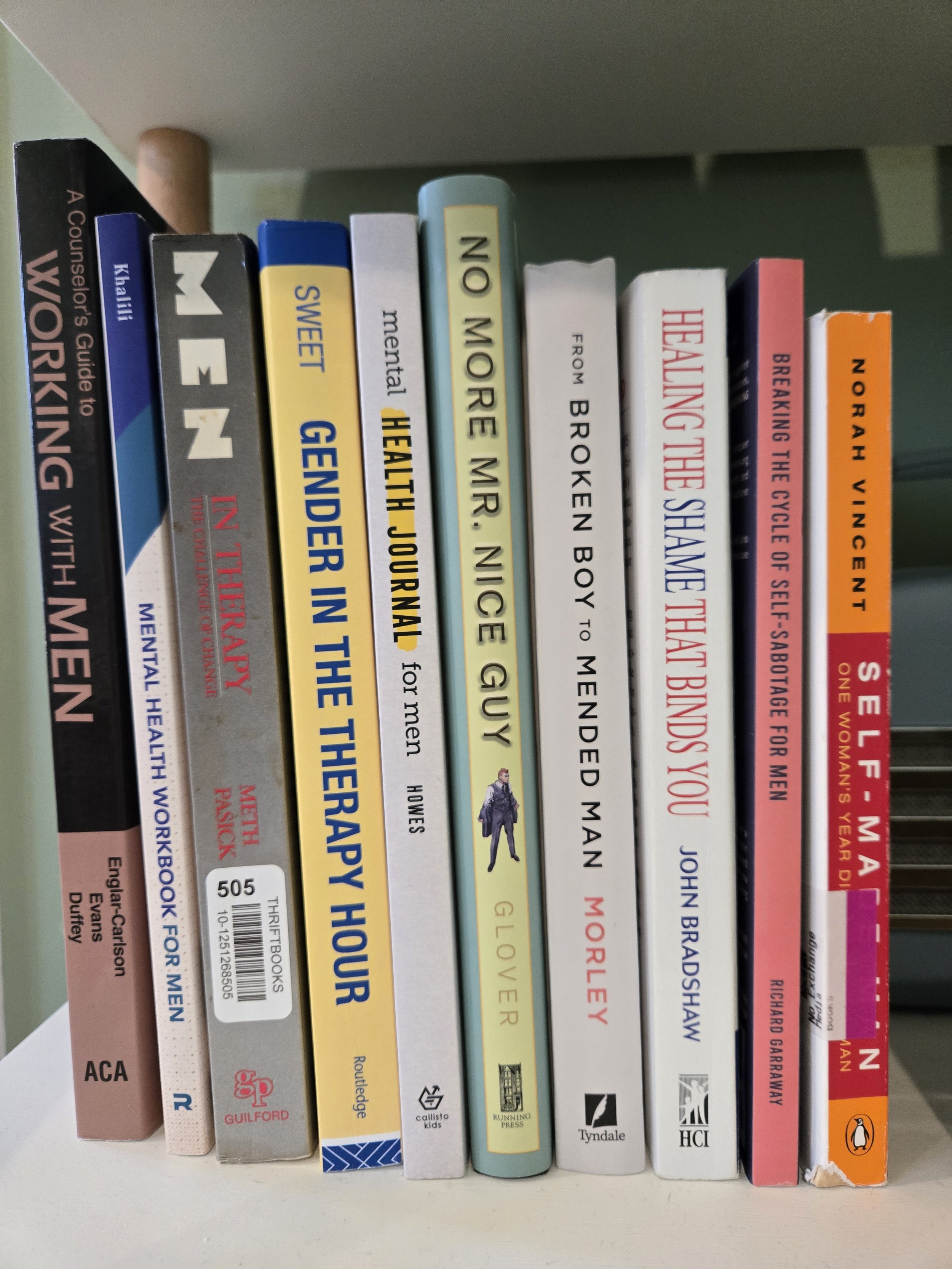 A row of books on a shelf, with titles partially visible including topics like mental health, therapy, and self-help.