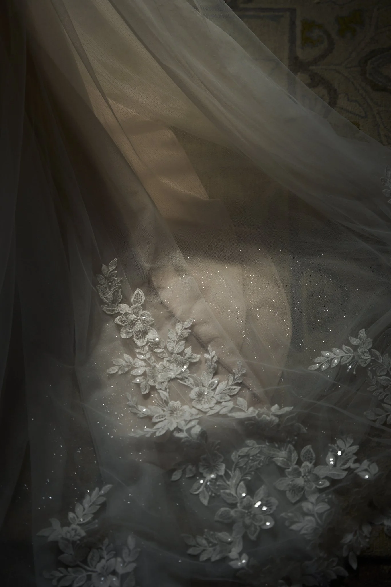 Close-up of a sheer fabric with embroidered floral patterns and small sparkling embellishments.