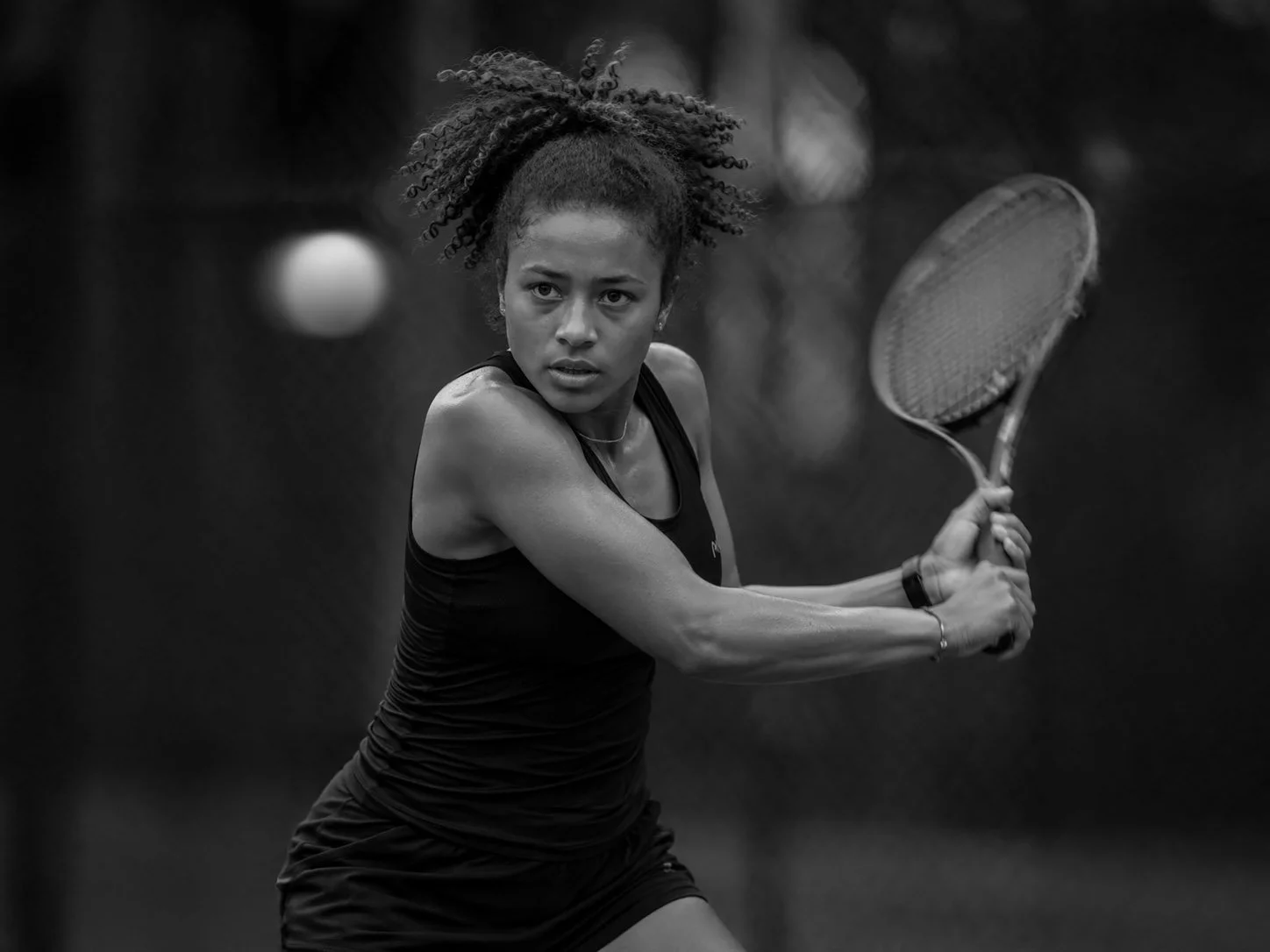 A woman playing tennis on an outdoor court, preparing to hit the ball with a racquet.