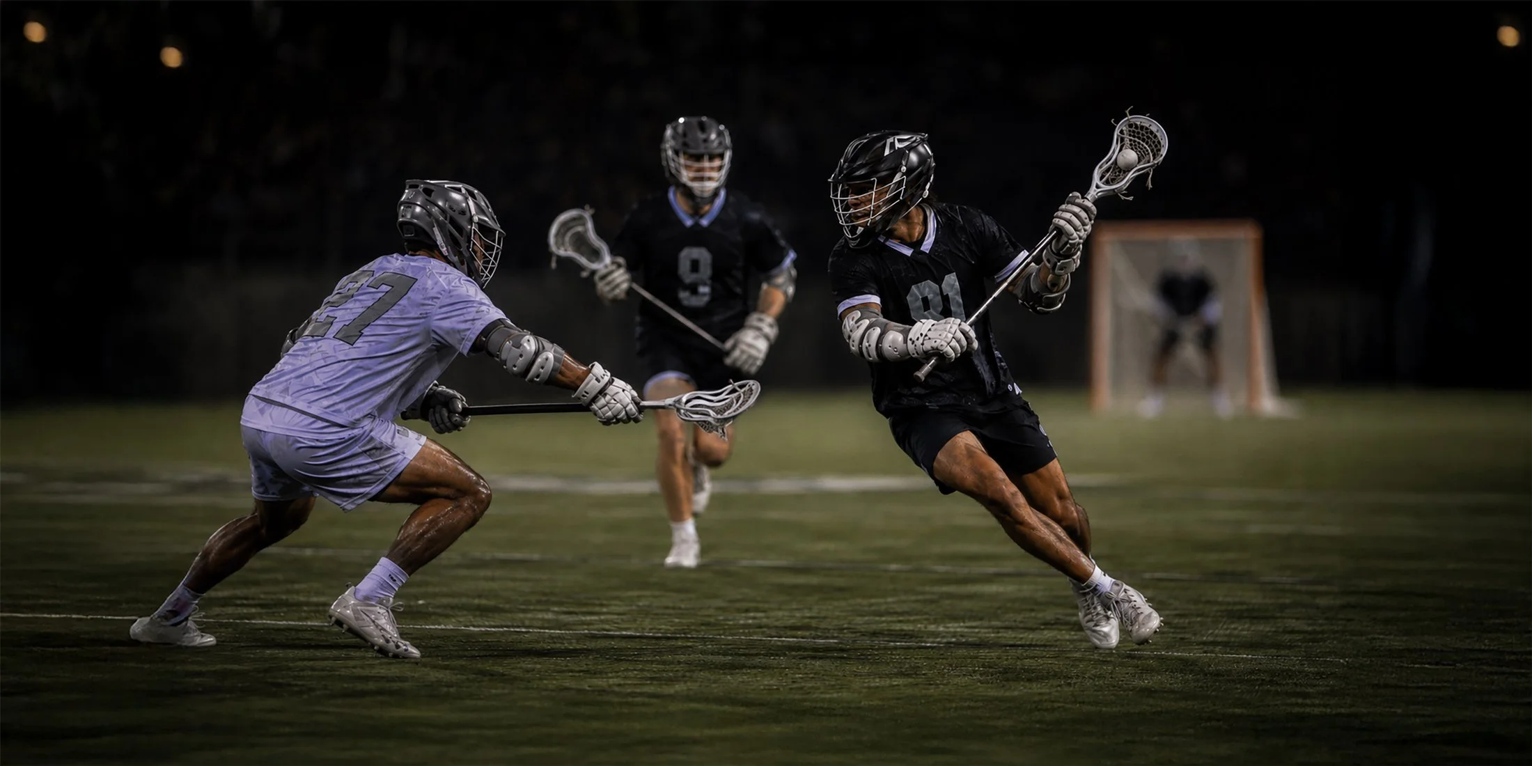 Lacrosse players competing on a field at night, with one player in black attempting to dodge a defender in light purple, and a goalkeeper in the background.
