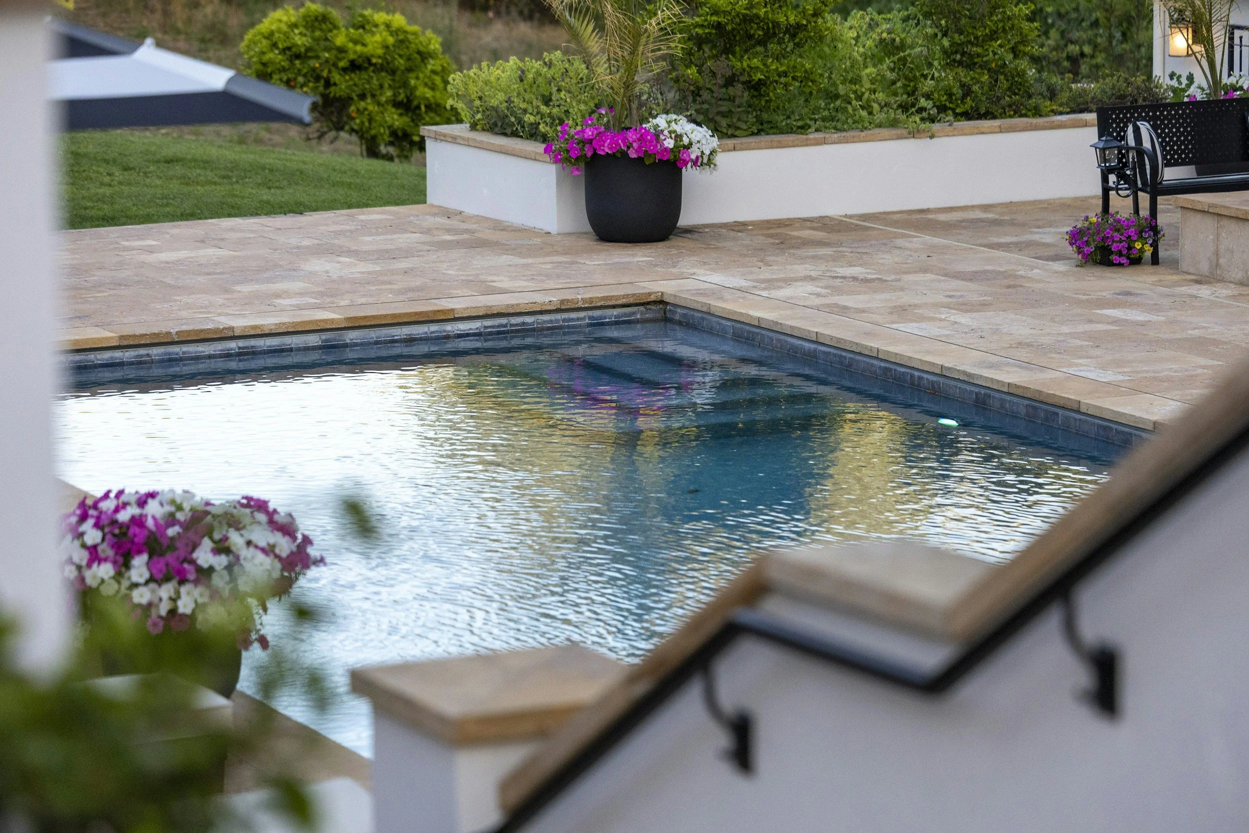 Backyard outdoor living space featuring a swimming pool, stone patio, landscaping, and thoughtfully placed garden elements. Aqua Terra Pool and Patio creates beautiful, functional outdoor spaces for homeowners throughout Cincinnati.