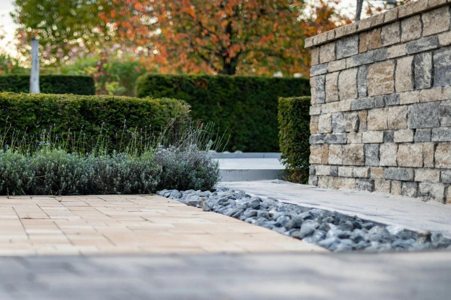 Outdoor living space featuring a brick patio, stone edging, landscaped greenery, and natural design elements. Aqua Terra Pool and Patio creates thoughtfully designed outdoor spaces throughout Cincinnati.
