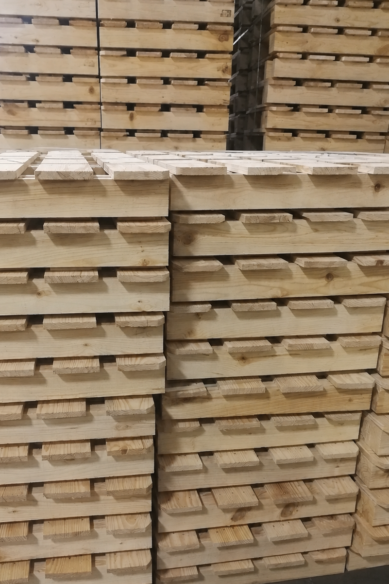 Stacks of wooden pallets arranged in a warehouse or storage area.