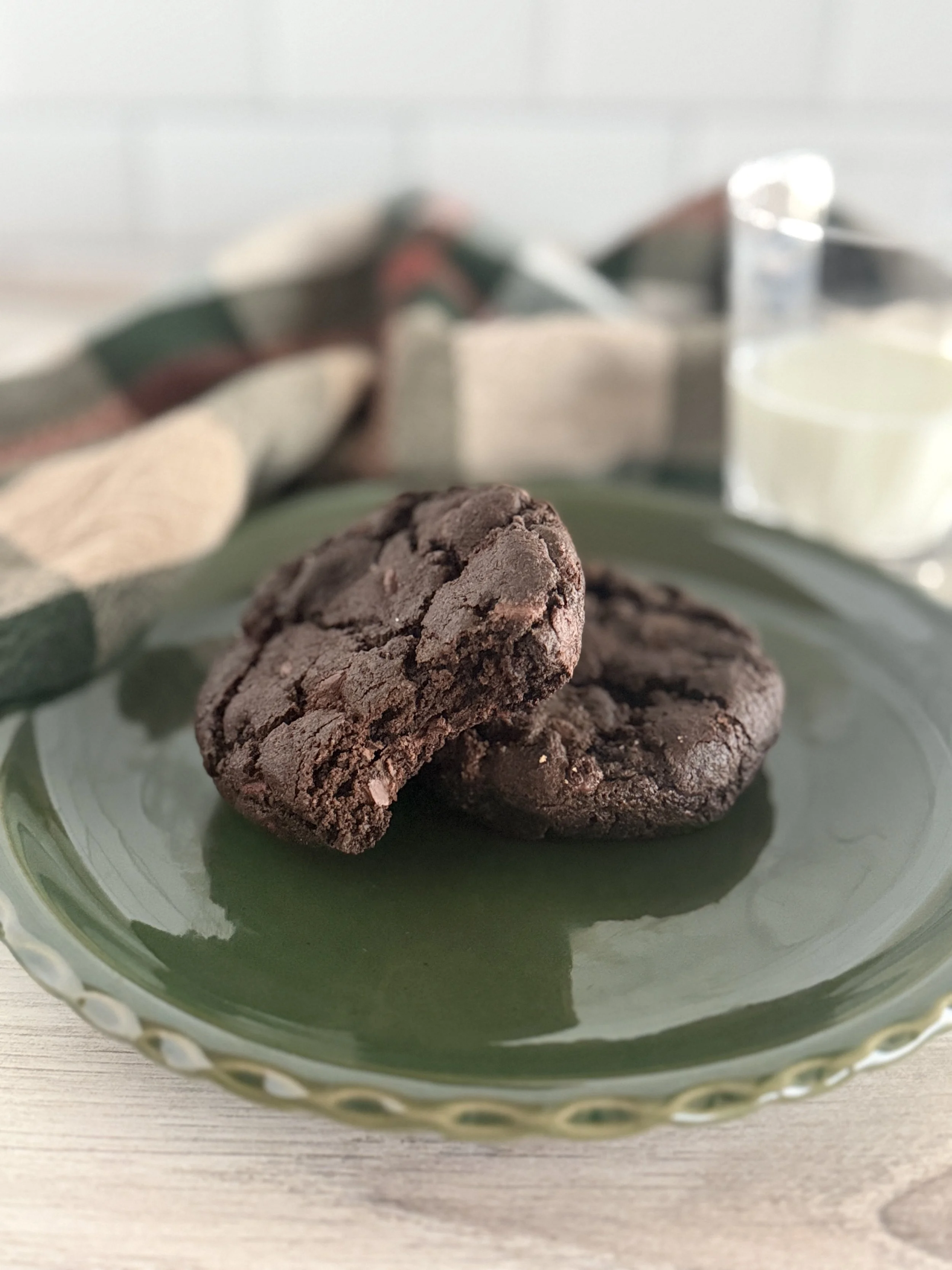 Two chococolate chocolate chip cookies on a green plate.