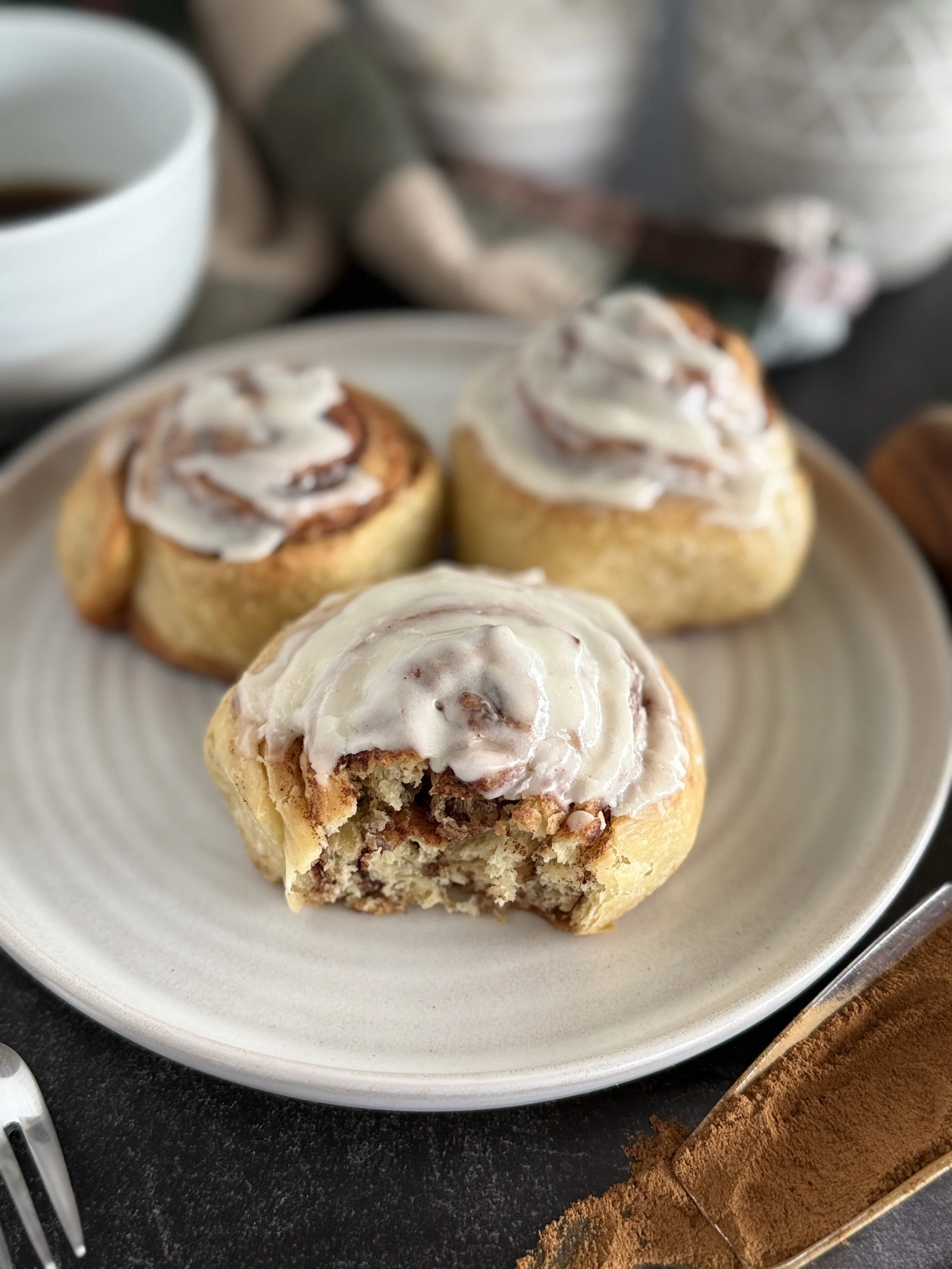 Three cinnamon rolls with one showing the inside of it.