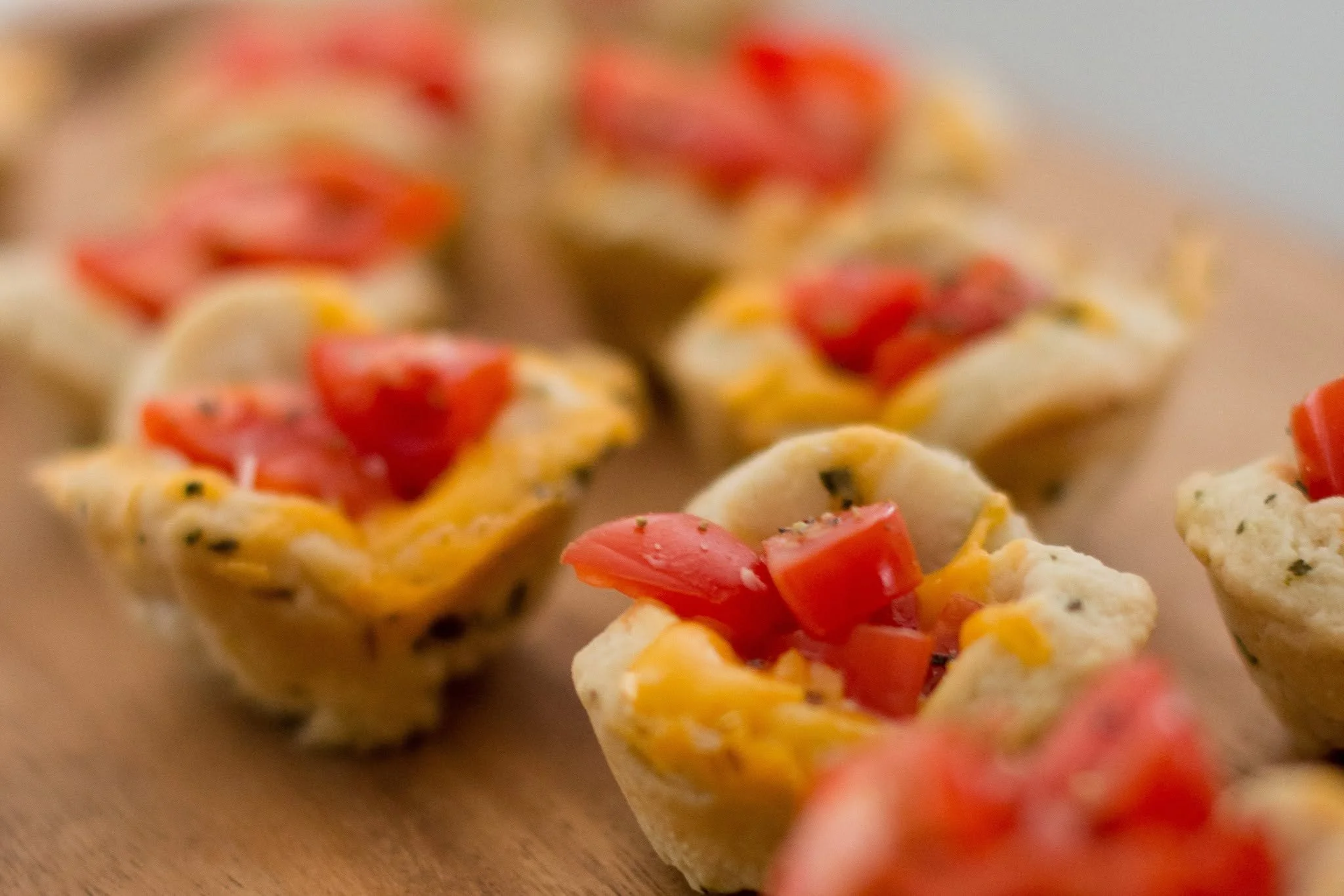 Close-up of savory pastry with chopped tomatoes and herb-seasoned cheese.