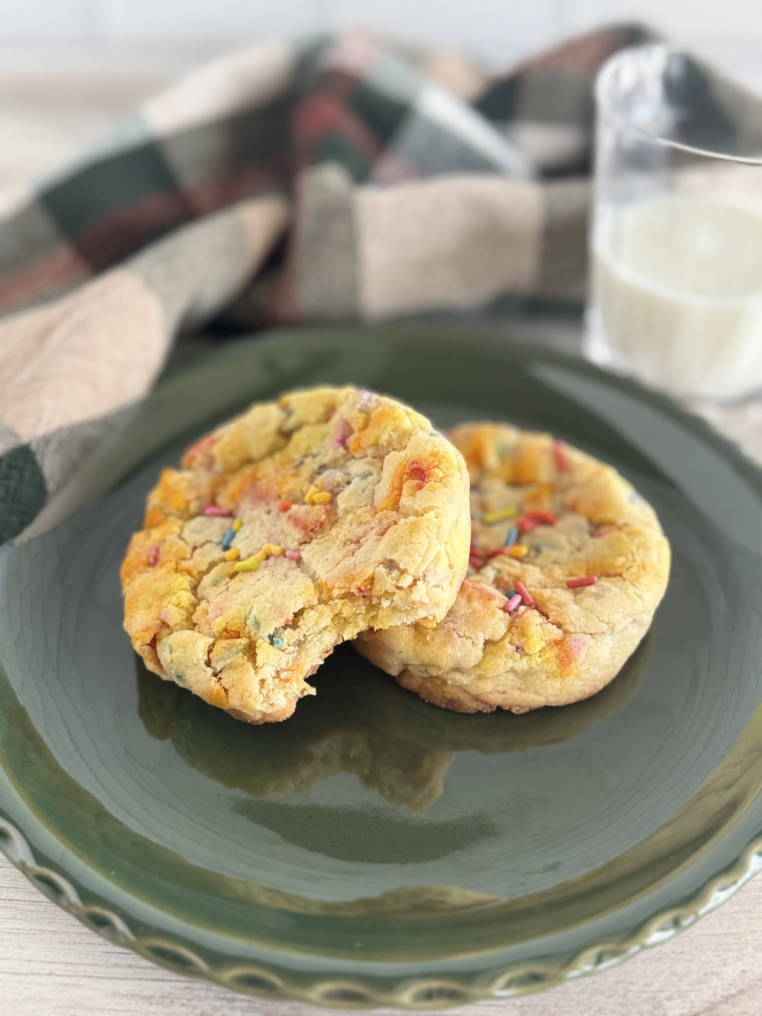 Two sprinkle cookies on a green plate.