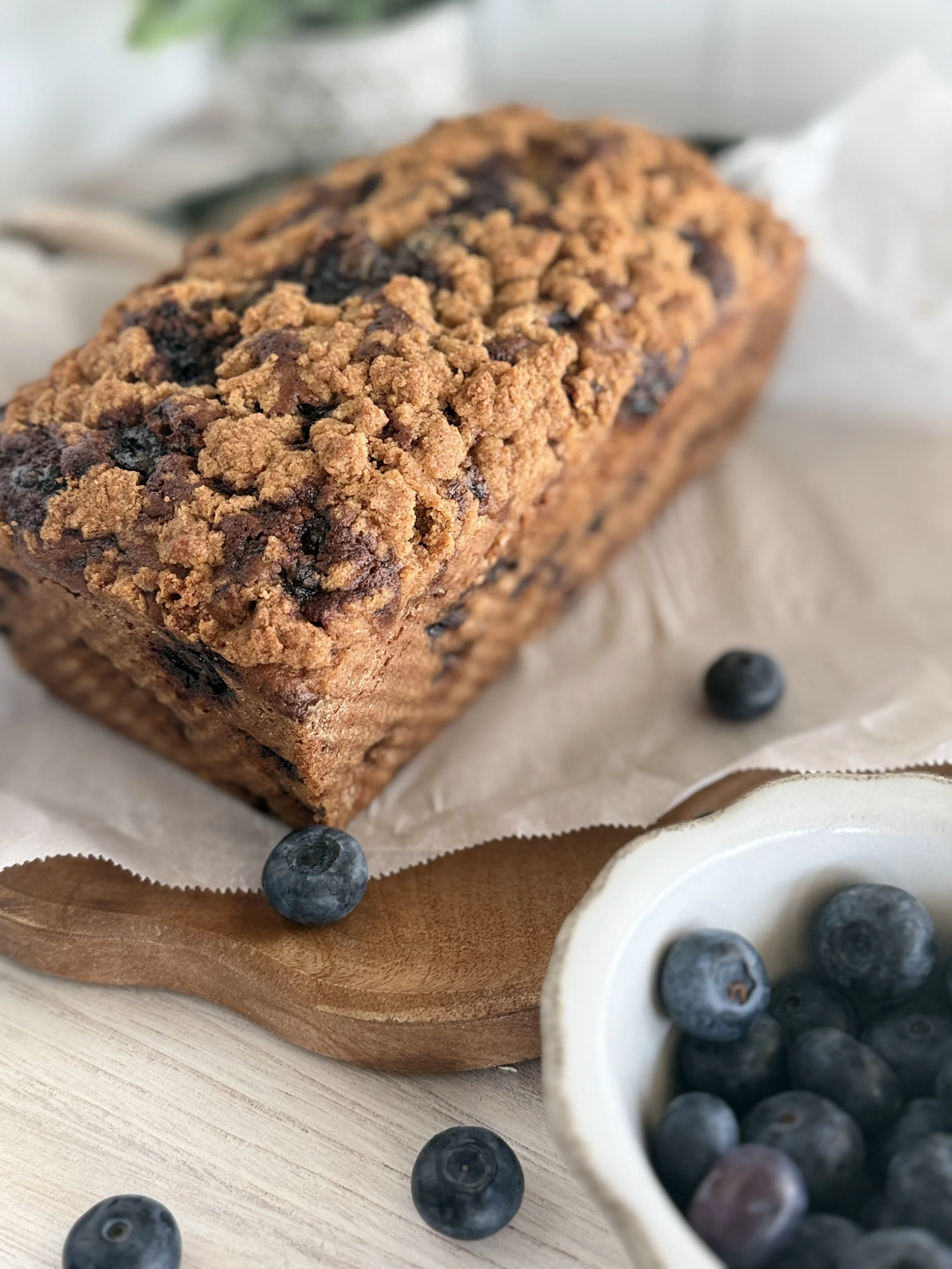 Close up of blueberry bread with crumble on top on a piece of parchment paper.
