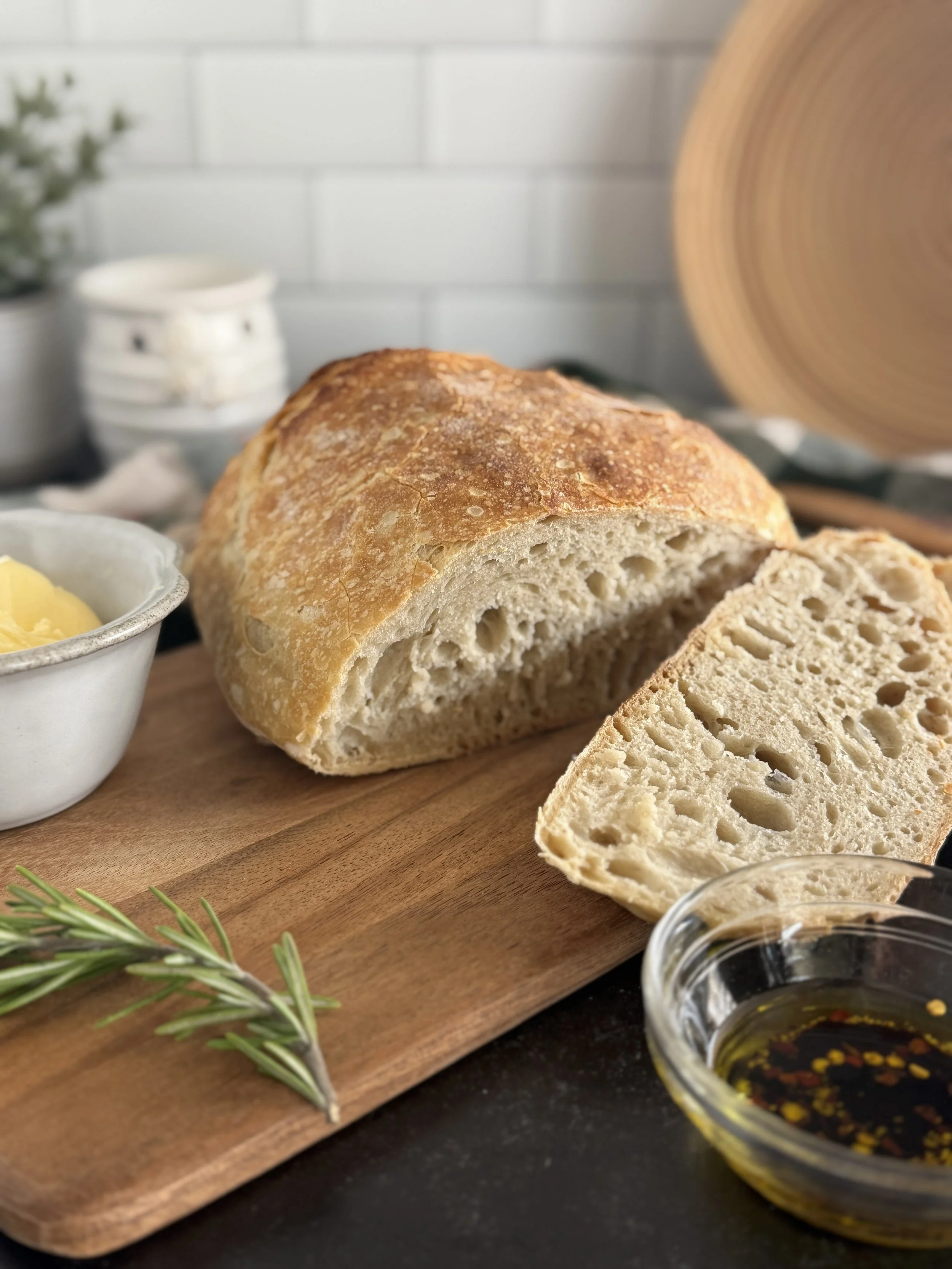 Close up of the inside of a crusty load of bread with a butter dish and a olive oil dish beside it.