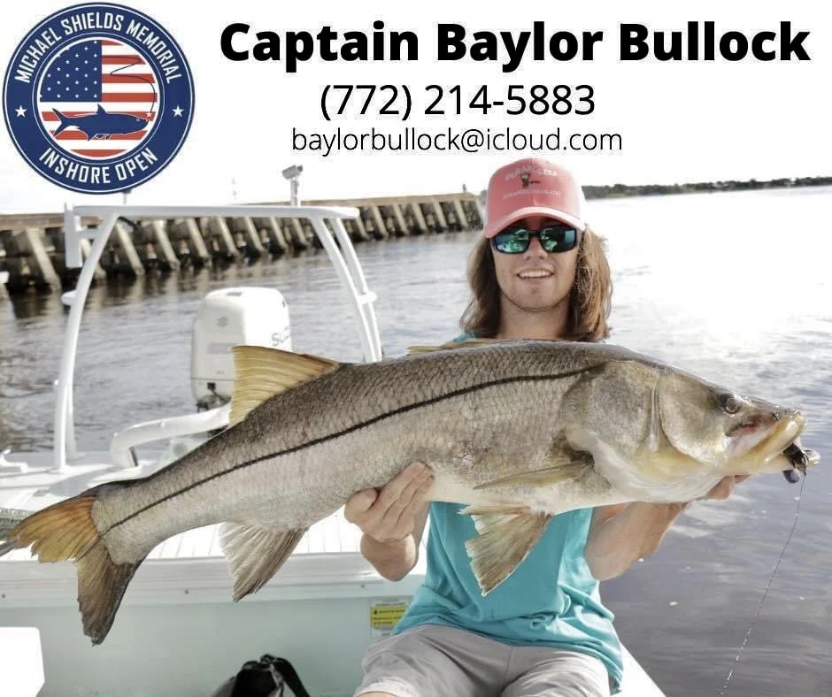 A man on a boat holding a large fish, with a water background and a dock in the distance. The boat has a logo and contact information for Captain Baylor Bullock.