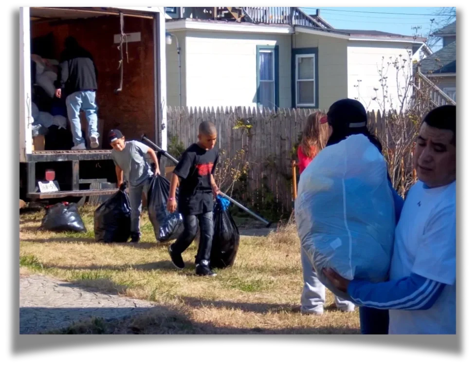 A series of people haul bags of supplies into a box truck