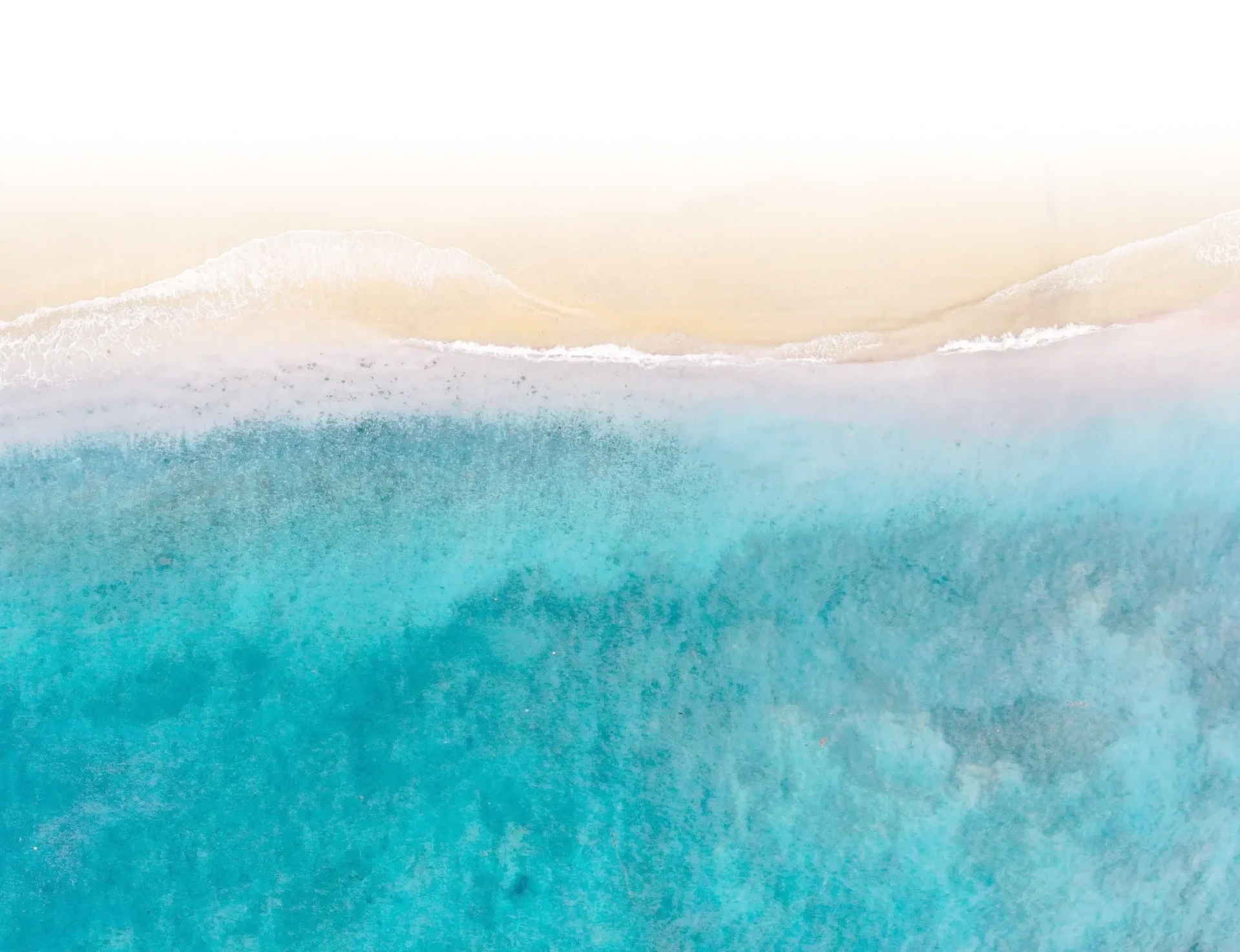 A photo of turquoise ocean waves and white surf, with a pale beige sandy shore.
