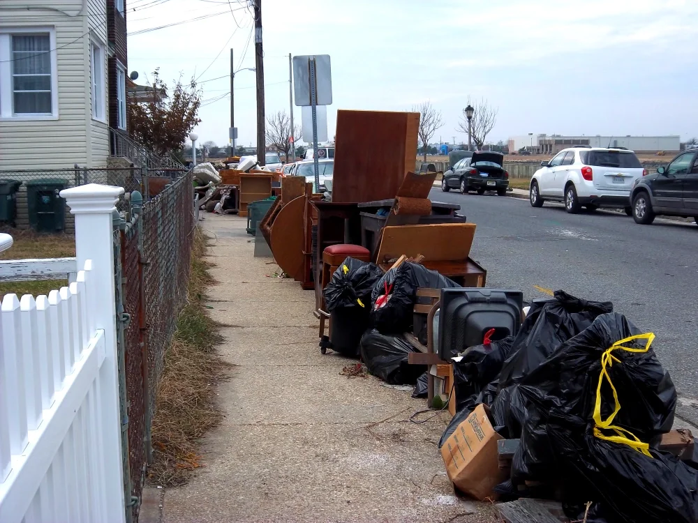 A view of a stretch of the road with piles of garbage and destroyed furniture 