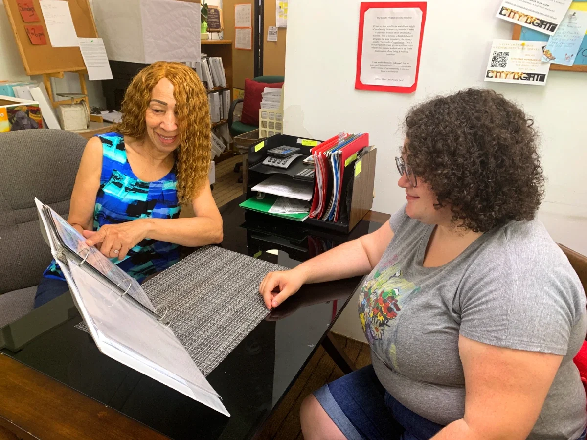 A woman points out a page to another woman during an orientation to a new volunteer.