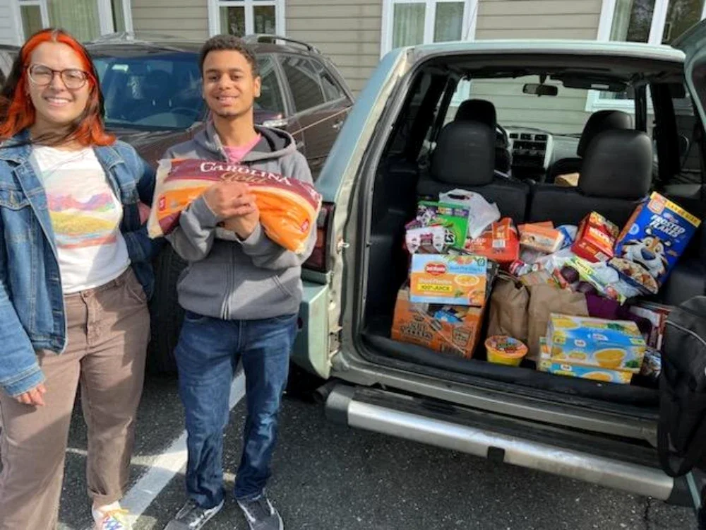 A man and a woman smile next to trunk of food