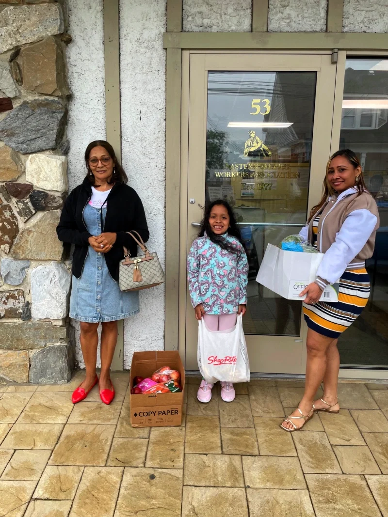 Two ESWA members a girl pose with food in front of ESWA's office