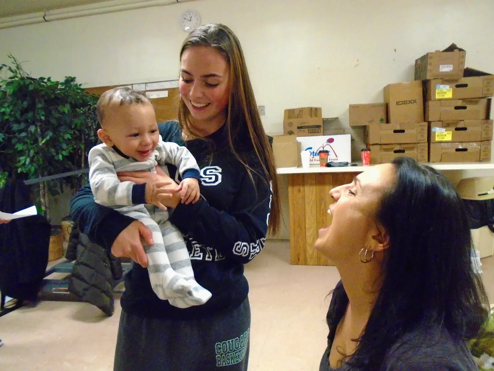 A smiling baby stares at a laughing woman