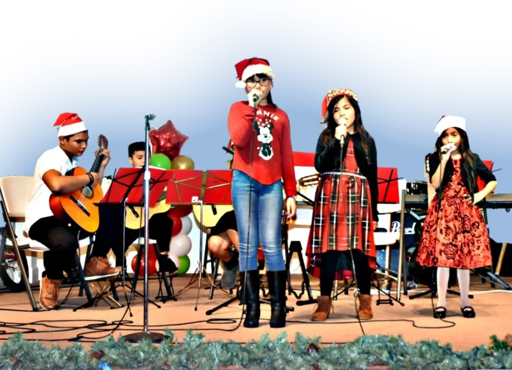 Children sing and play guitar wearing Santa hats