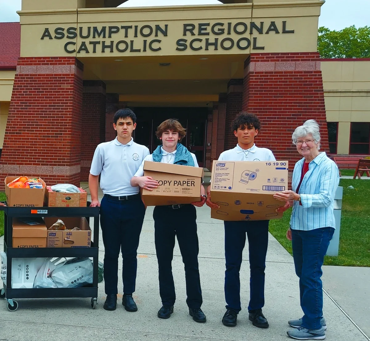 A woman poses next to students of the Assumption Regional Catholic School after a collection of food for ESWA