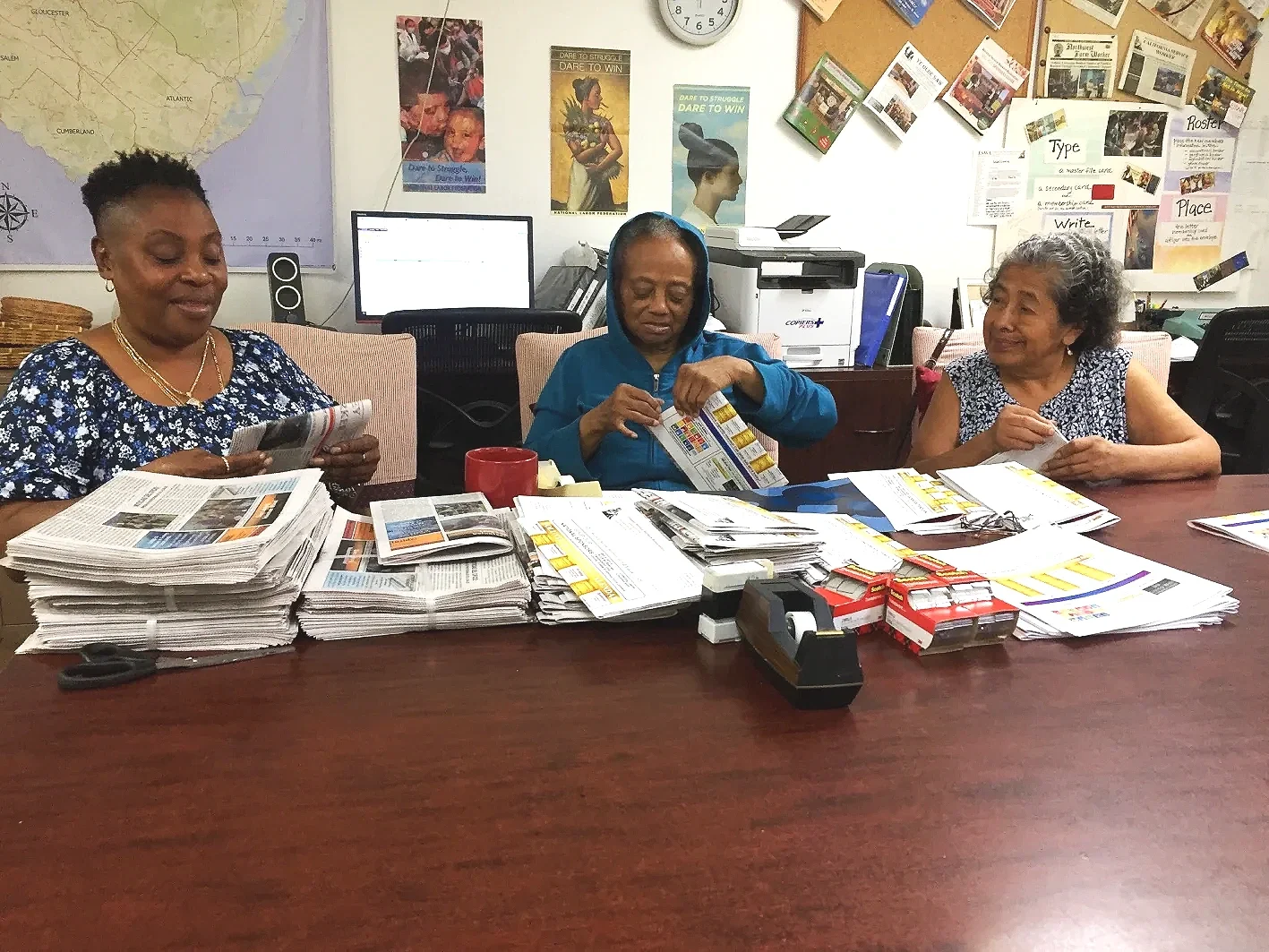 Three women fold newspapers